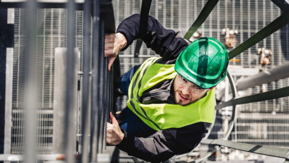 Young male technician climbing ladder in industry
