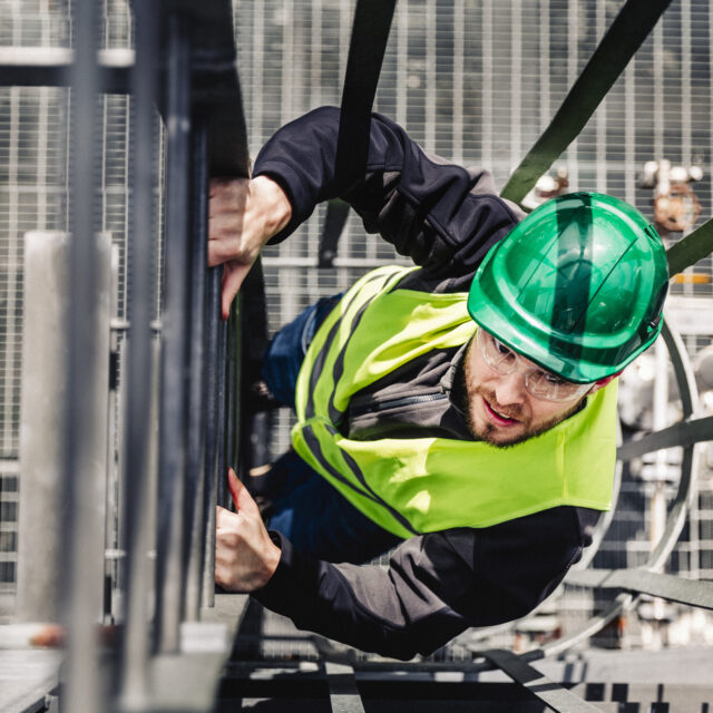 Young male technician climbing ladder in industry