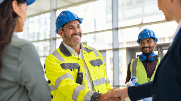 Mature architect and contractor shaking hands at construction site