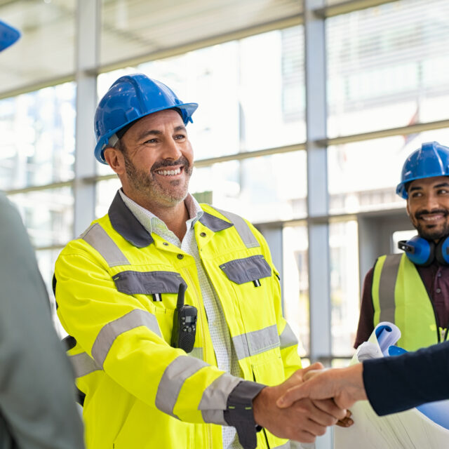 Mature architect and contractor shaking hands at construction site