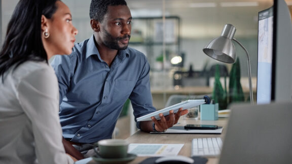 Collaboration, computer and tablet with business people in office together for planning or project management. Feedback, teamwork or technology with employee man and woman in workplace for research